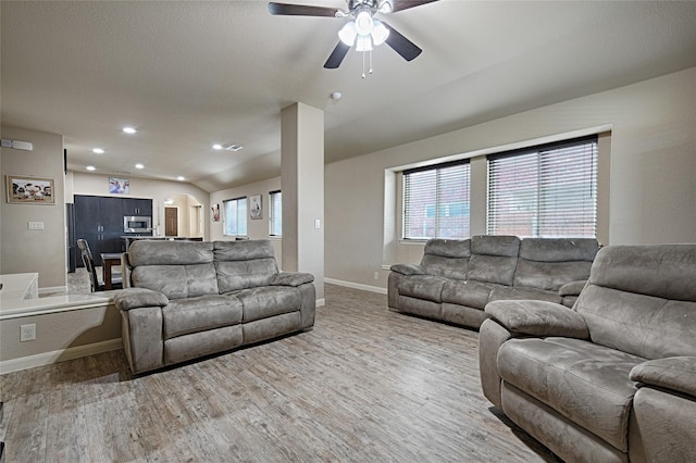 living room featuring recessed lighting, a ceiling fan, arched walkways, baseboards, and light wood-style flooring
