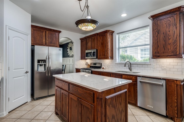 kitchen with a sink, decorative backsplash, light tile patterned flooring, stainless steel appliances, and a kitchen island
