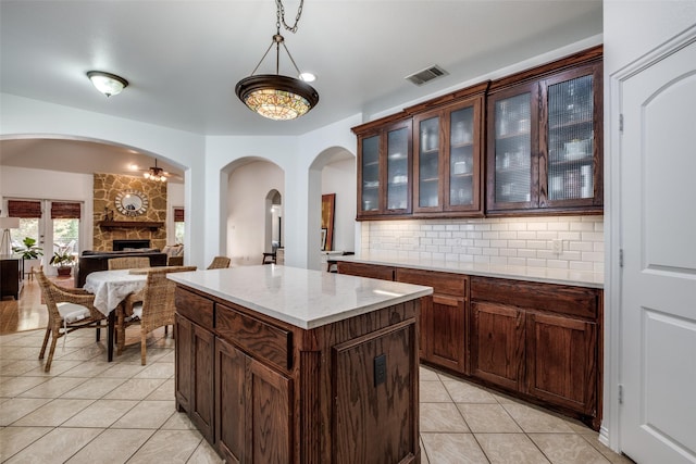 bar featuring visible vents, light tile patterned floors, arched walkways, a fireplace, and tasteful backsplash