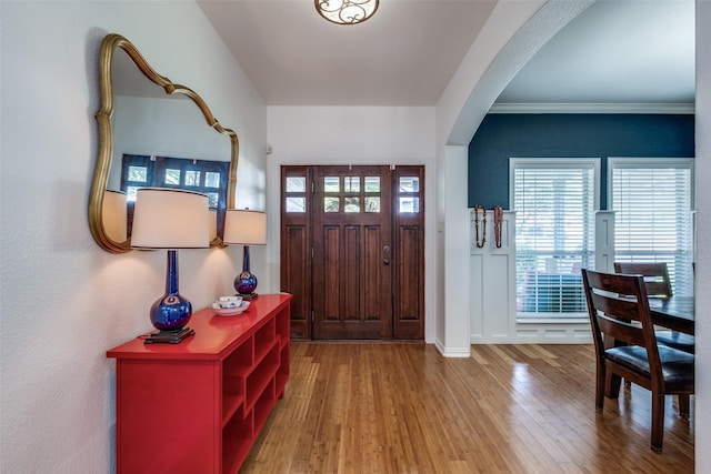 entrance foyer with arched walkways, wood finished floors, and baseboards