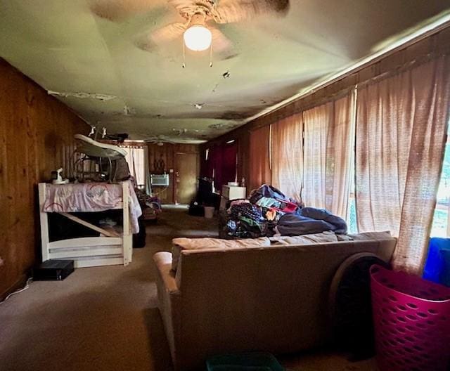 misc room with wooden walls, carpet, and a ceiling fan