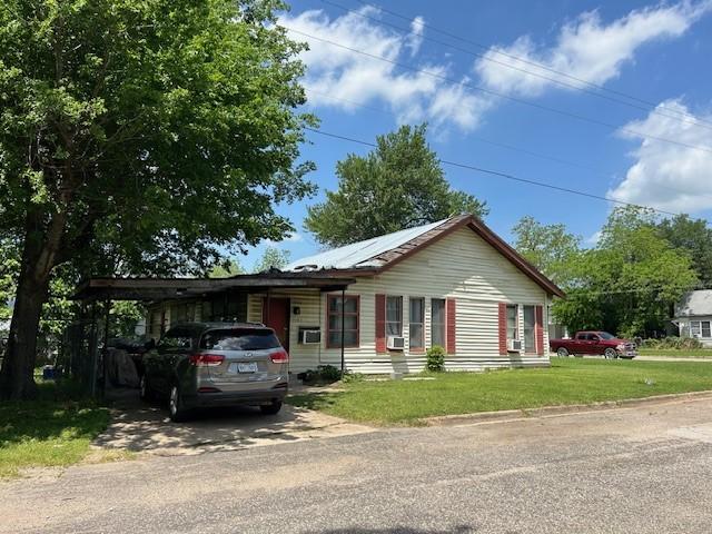 ranch-style home featuring driveway, a front yard, and an attached carport