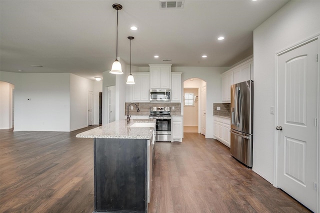 kitchen featuring a sink, decorative backsplash, arched walkways, appliances with stainless steel finishes, and visible vents