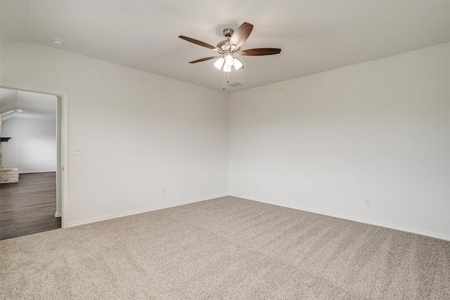 carpeted spare room featuring lofted ceiling, baseboards, ceiling fan, and visible vents