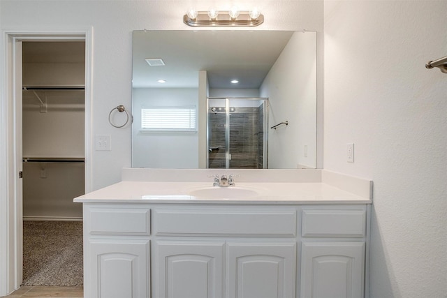 full bathroom with a shower stall, a spacious closet, vanity, and visible vents