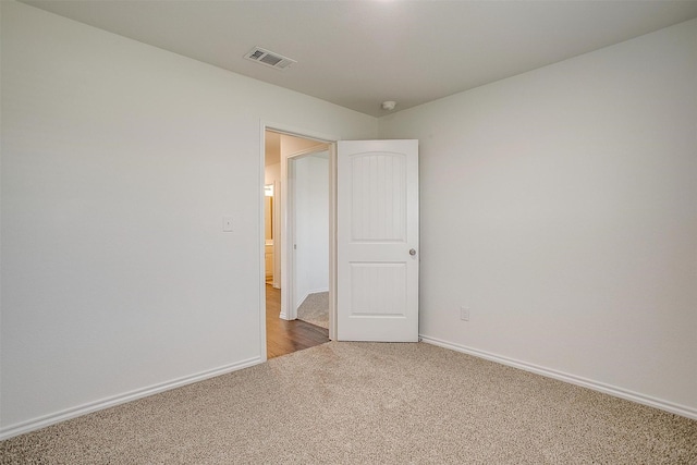 carpeted empty room featuring baseboards and visible vents