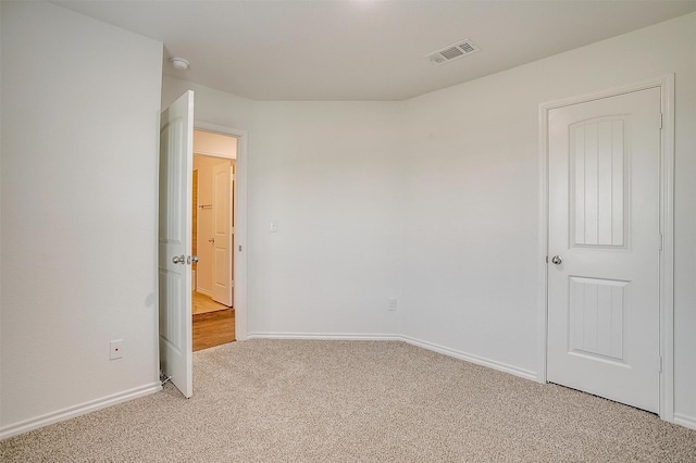 spare room with baseboards, visible vents, and light colored carpet