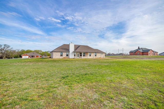 rear view of property featuring a lawn and a chimney