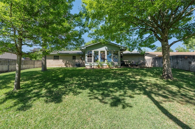back of house with a lawn and a fenced backyard