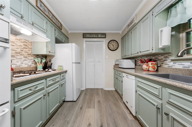kitchen with white appliances, green cabinets, a sink, and tasteful backsplash