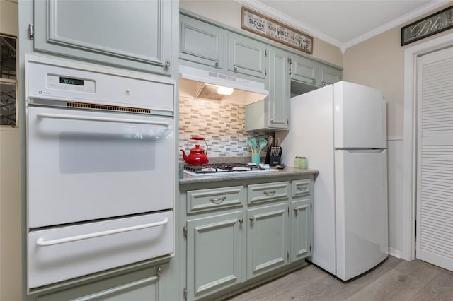 kitchen featuring a warming drawer, light wood-style floors, white appliances, crown molding, and under cabinet range hood