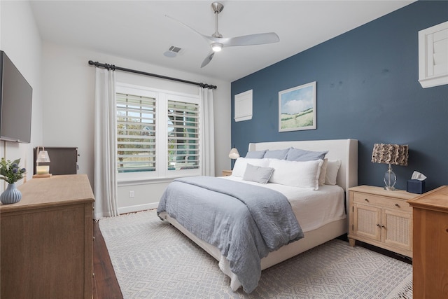 bedroom with baseboards, a ceiling fan, light wood finished floors, and visible vents