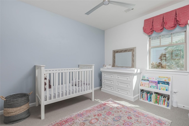 carpeted bedroom with a nursery area, visible vents, baseboards, and ceiling fan