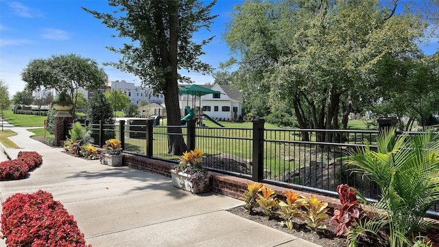 view of home's community with fence, a yard, and a playground
