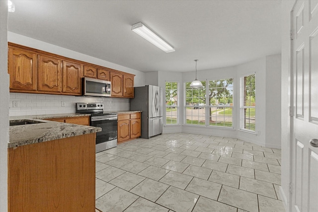 kitchen with light stone countertops, stainless steel appliances, brown cabinets, and backsplash