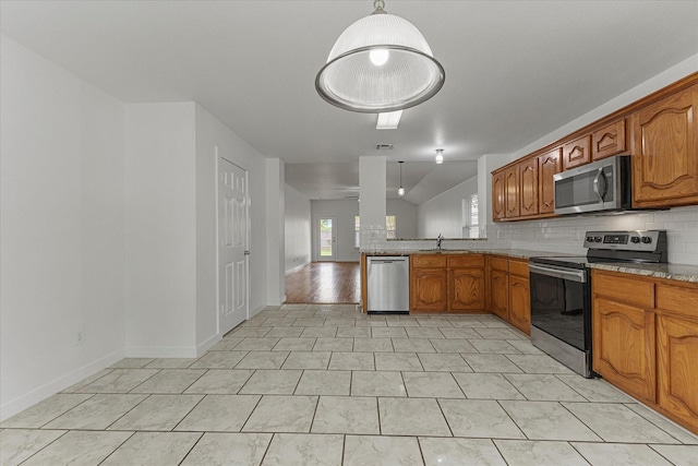 kitchen with backsplash, brown cabinets, stainless steel appliances, and a sink