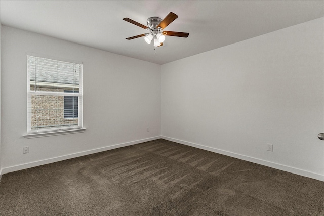 empty room with dark colored carpet, baseboards, and ceiling fan