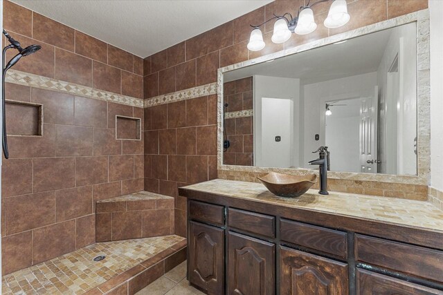 full bath with a tile shower, tile patterned flooring, vanity, and ceiling fan