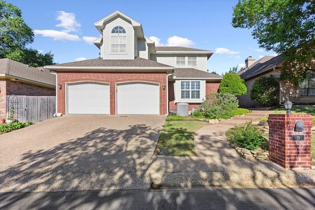 traditional home with driveway, a shingled roof, fence, a garage, and brick siding