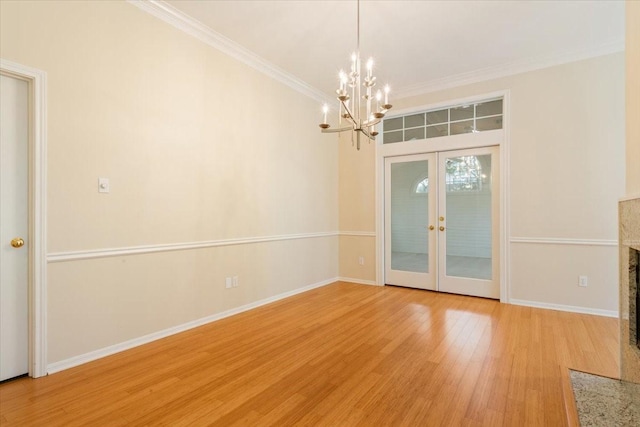 unfurnished dining area with a chandelier, light wood finished floors, baseboards, and ornamental molding