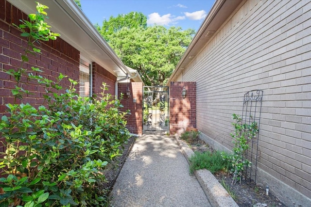 view of side of property featuring brick siding and a gate