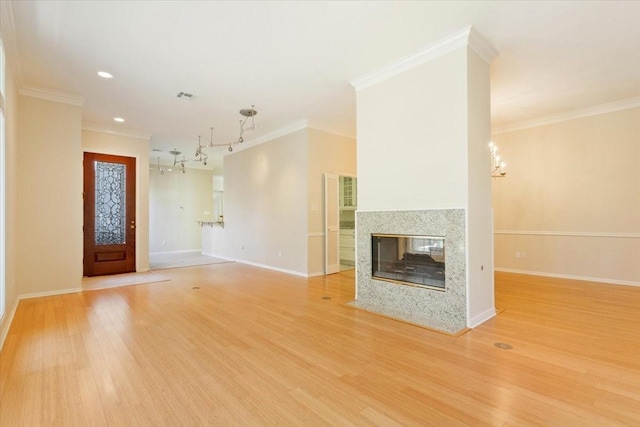 unfurnished living room with baseboards, an inviting chandelier, light wood-style floors, and crown molding