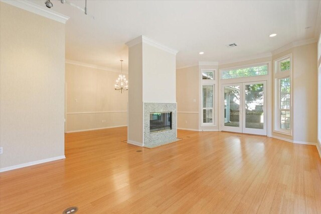 unfurnished living room featuring light wood-type flooring, baseboards, a chandelier, a multi sided fireplace, and ornamental molding