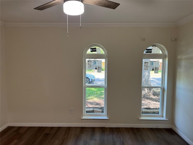 empty room with a ceiling fan, dark wood-style flooring, crown molding, and baseboards