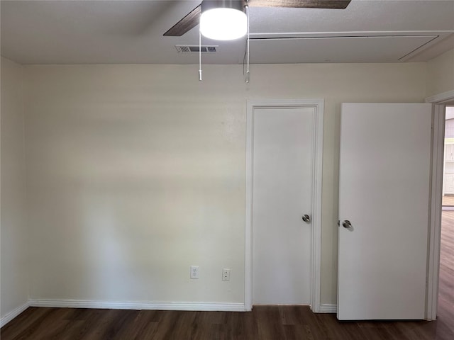 unfurnished room featuring attic access, wood finished floors, visible vents, and baseboards