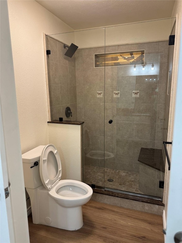 full bathroom featuring a shower stall, toilet, and wood finished floors