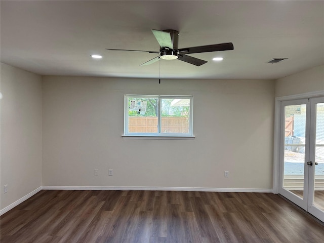 empty room with baseboards, visible vents, a ceiling fan, and dark wood-style floors