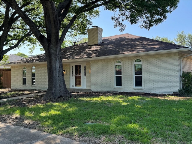 ranch-style home featuring brick siding, a front yard, and a chimney