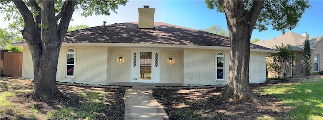 bungalow featuring a chimney and brick siding
