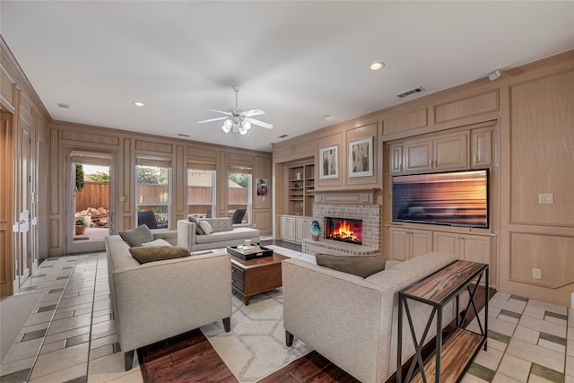 4524 Tuscany Dr, Plano, TX 75093 - living area featuring built in shelves, a brick fireplace, ceiling fan, wooden walls, and ornamental molding