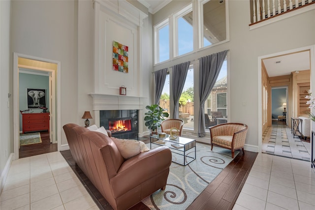 4524 Tuscany Dr, Plano, TX 75093 - living room featuring a towering ceiling, a tile fireplace, baseboards, tile patterned flooring, and crown molding