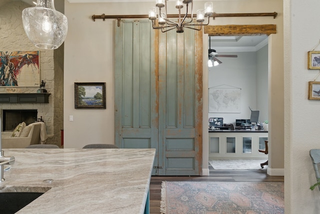 kitchen featuring a fireplace, wood finished floors, crown molding, and ceiling fan with notable chandelier
