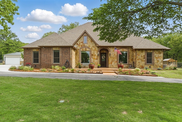 view of front of property with brick siding, a front lawn, roof with shingles, and stone siding