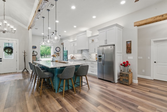 kitchen with a large island, white cabinetry, wood finished floors, and stainless steel fridge