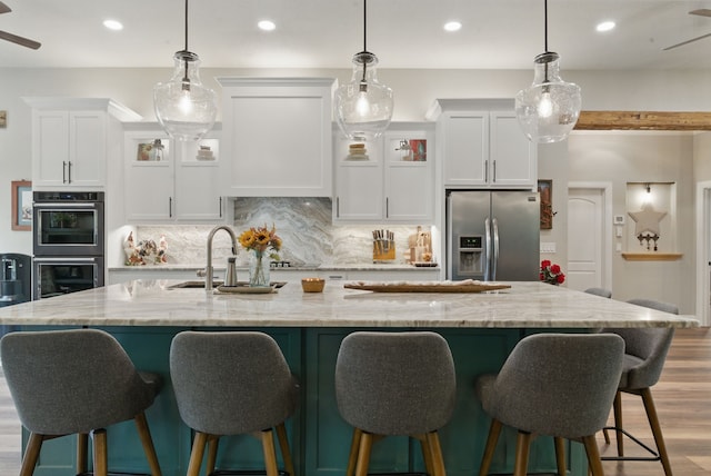 kitchen with backsplash, stainless steel fridge, multiple ovens, and a ceiling fan