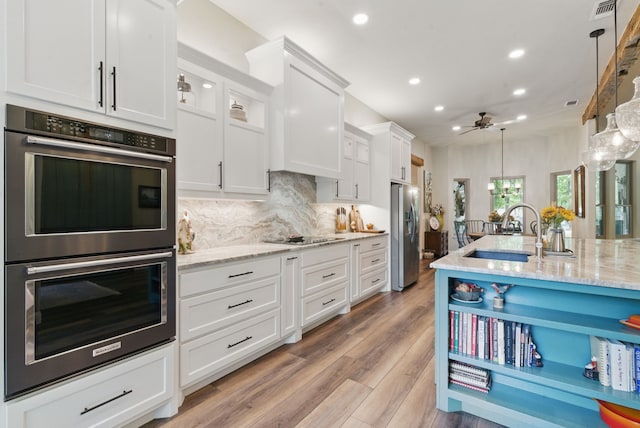 kitchen with recessed lighting, a sink, appliances with stainless steel finishes, white cabinetry, and ceiling fan with notable chandelier