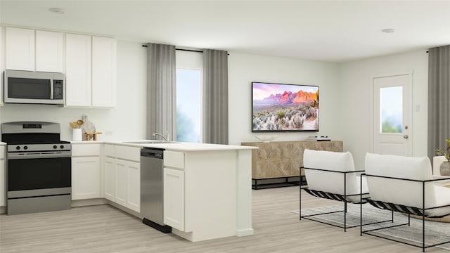 kitchen featuring a peninsula, light wood-style flooring, stainless steel appliances, and a sink