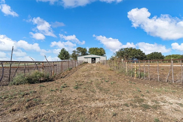 view of yard featuring a rural view, a pole building, fence, and an outdoor structure