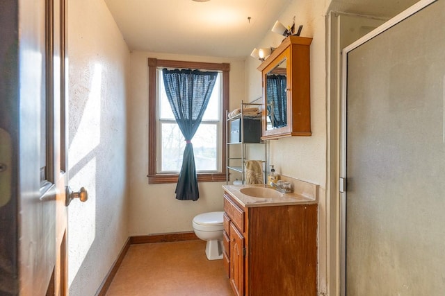 bathroom featuring baseboards, vanity, a shower stall, and toilet