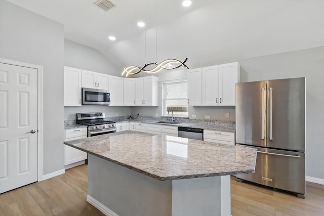 kitchen featuring a sink, light wood-type flooring, vaulted ceiling, visible vents, and appliances with stainless steel finishes