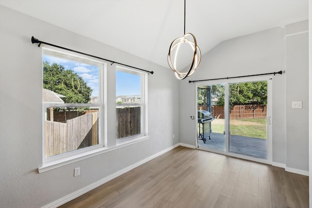 unfurnished dining area featuring lofted ceiling, wood finished floors, and baseboards