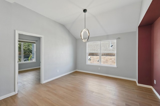 unfurnished dining area featuring vaulted ceiling, light wood finished floors, and baseboards