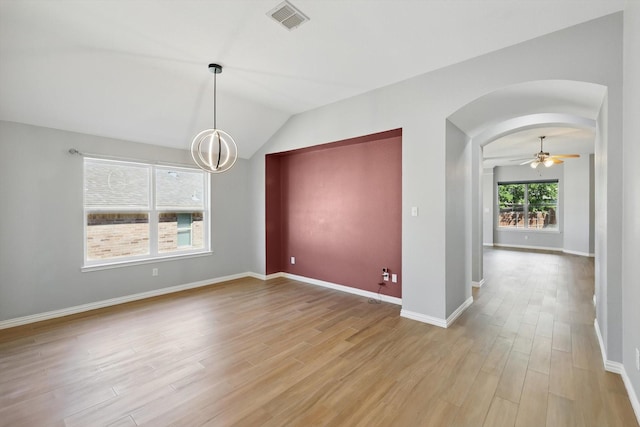 unfurnished dining area with vaulted ceiling, visible vents, arched walkways, light wood-type flooring, and baseboards