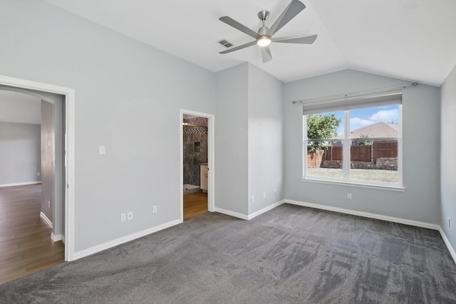 unfurnished bedroom with vaulted ceiling, visible vents, arched walkways, carpet floors, and baseboards