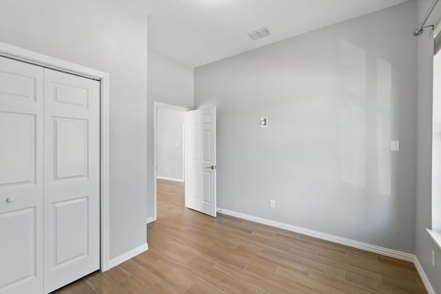 unfurnished bedroom featuring a closet, light wood-style floors, visible vents, and baseboards