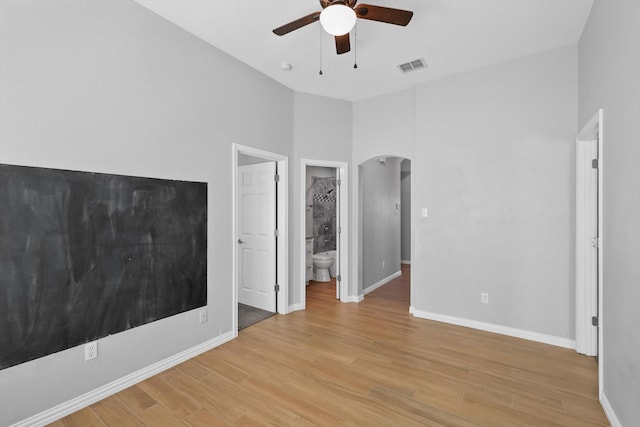 unfurnished bedroom featuring light wood-type flooring, baseboards, visible vents, and arched walkways